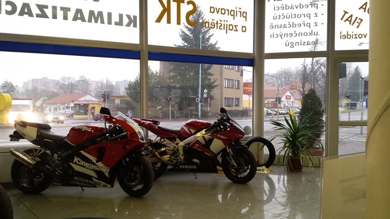 Výstavní prostor autoservisu s motorkami Kawasaki a Yamaha